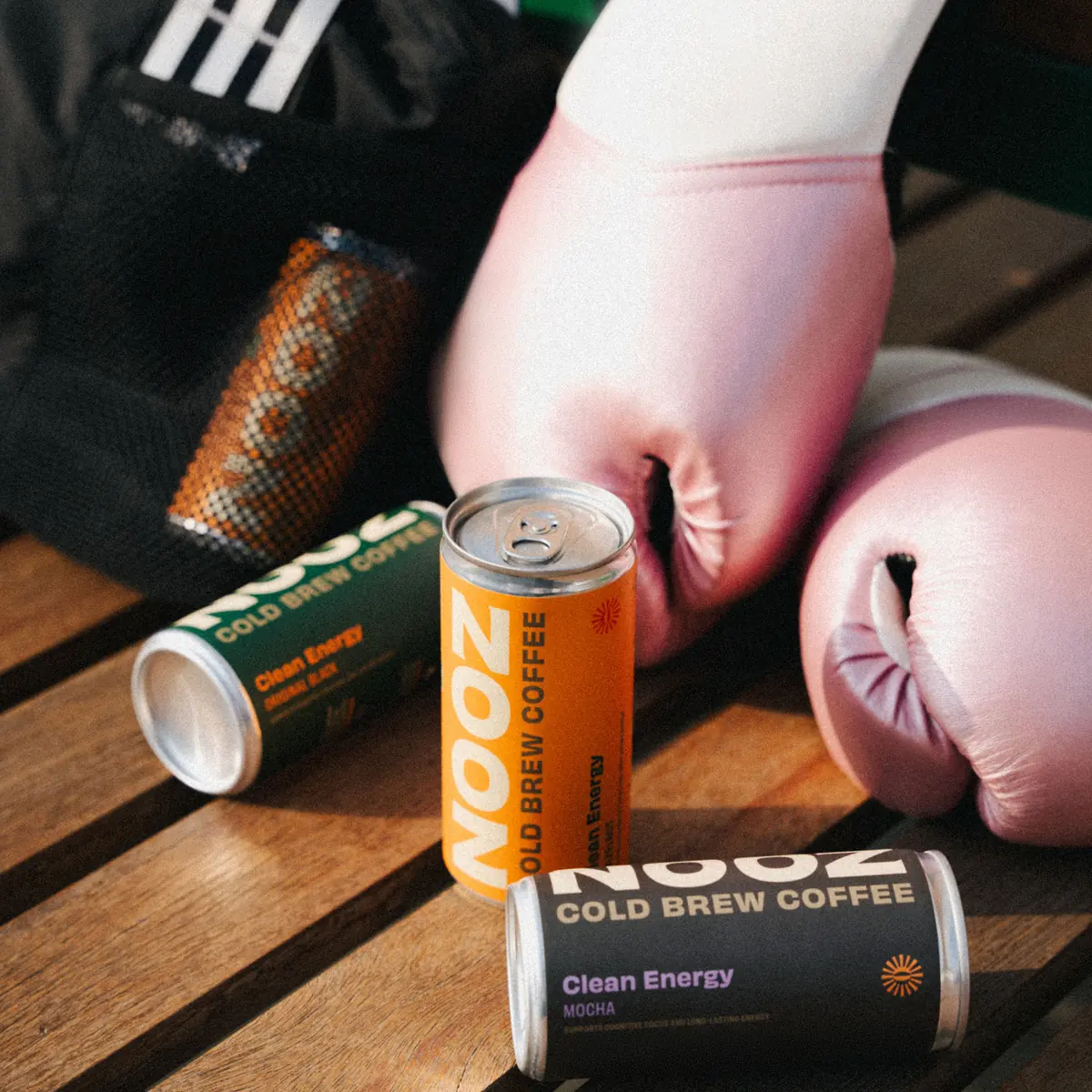 NOOZ cans beside boxing gloves and a gym bag